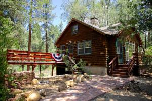 a log cabin in the woods with a flag at Ahwahnee-be Vintage Cabin - Walk to town! in Idyllwild