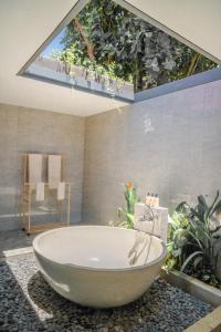 a bathroom with a large tub with plants on the wall at Ocean Paradise Bali in Buleleng