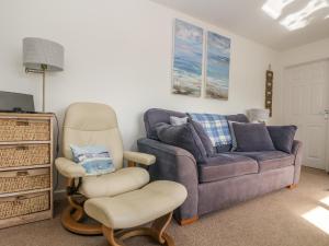 a living room with a couch and a chair at Cockle Island Cott in Porthallow