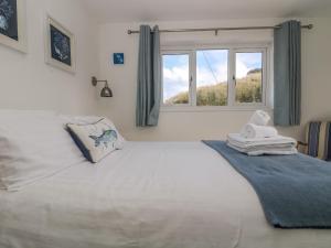 1 dormitorio con 1 cama blanca grande y ventana en Cockle Island Cott en Porthallow
