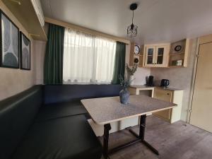 una sala de estar con una mesa con un jarrón. en Toscane aan zee Caravan,- Mobile home- Chalet ZR8 Viareggio, Pisa, Lucca en Torre del Lago Puccini