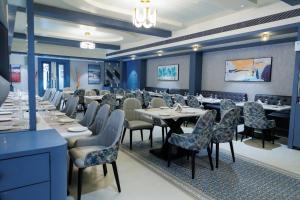 AJ GRAND ELITE HOTEL في منغالور: غرفة طعام مع طاولات وكراسي في مطعم