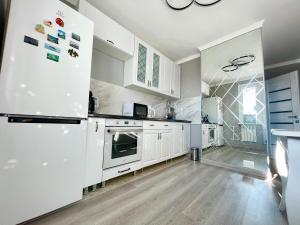 kuchnia z białymi szafkami i lodówką w obiekcie Brand New Apartment Main Road w Kiszyniowie