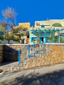 un muro di pietra con un cancello blu di fronte a una casa di Sevasti Studios a Panormos Kalymnos