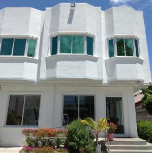 una casa blanca con ventanas y plantas delante de ella en Sillero Painting Gallery and Hostel en Dumaguete