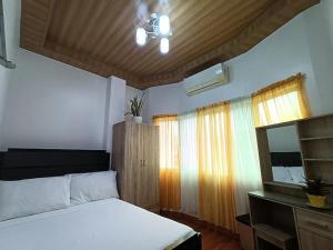 1 dormitorio con cama blanca y ventana en Sillero Painting Gallery and Hostel en Dumaguete
