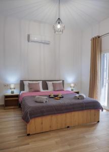 a white bedroom with a large bed with pink sheets at Kleopatra's maisonette in Gázion