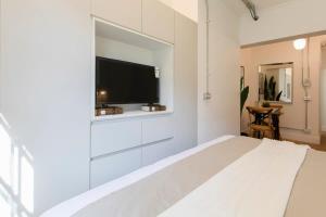 a bedroom with a large white bed with a flat screen tv at Studio en la Calle Monjitas Corazon de Santiago in Santiago