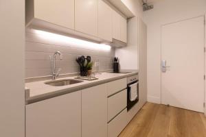 uma cozinha com armários brancos e um lavatório em Acogedor y Luminoso Studio en Monjitas ServicioHOM em Santiago