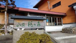 un bâtiment avec un panneau devant lui dans l'établissement 山荘梶ヶ森, à Ōtakuchi