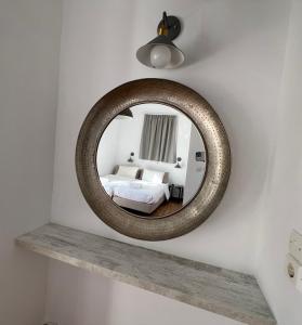 a round mirror on a wall with a bed at Nikos studios in Livadia