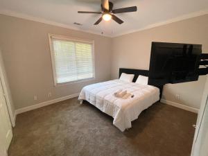 a bedroom with a bed with a ceiling fan and a flat screen tv at 2 Minute Walk To Gate 1 of Masters in Augusta