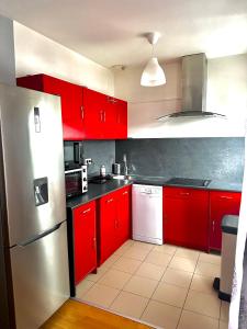 a kitchen with red cabinets and a silver refrigerator at Appartement Entier Montespan - Parking Privé in Évry-les-Châteaux