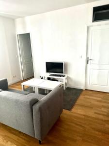 a living room with a couch and a tv at Appartement Entier Montespan - Parking Privé in Évry-les-Châteaux