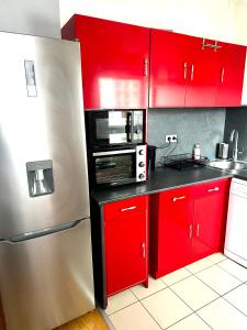 a kitchen with red cabinets and a stainless steel refrigerator at Appartement Entier Montespan - Parking Privé in Évry-les-Châteaux