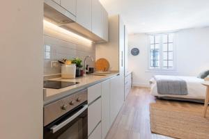 a kitchen with white cabinets and a bed in the background at Estancia Memorable en Santiago Depto Studio in Santiago