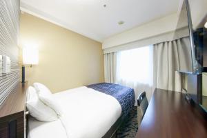 ein Hotelzimmer mit einem Bett und einem Fenster in der Unterkunft APA Hotel Midosuji-Honmachi-Ekimae in Osaka
