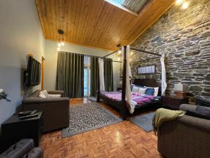 西姆拉的住宿－SaffronStays Ekam, Chail - forest villa near Chail cricket ground，一间带床和石墙的客厅