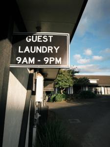a sign for a guest laundry on the side of a building at Oakwood Manor Motor Lodge in Auckland
