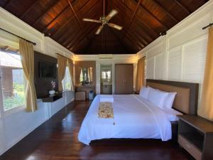 a bedroom with a white bed with a ceiling fan at Balangan Surf Resort in Jimbaran