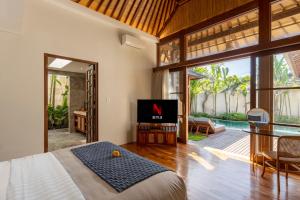 乌布Asvara Villa Ubud by Ini Vie Hospitality的一间卧室配有一张床、一台电视和一个庭院。