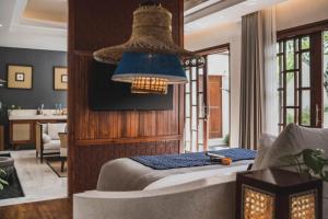 a bedroom with a bed and a chandelier at Asvara Villa Ubud by Ini Vie Hospitality in Ubud