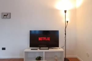 una TV a schermo piatto seduta sopra un tavolo bianco di Vicino Zoncolan+Netflix e Wifi a Treppo Carnico