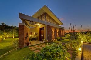 a brick house with a garden at dusk at The Fern Royal Farm Resort, Anjar in Anjār