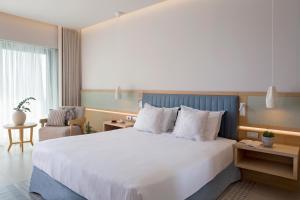 a hotel room with a large bed and a chair at Ammoa Luxury Hotel & Spa Resort in Nikiti