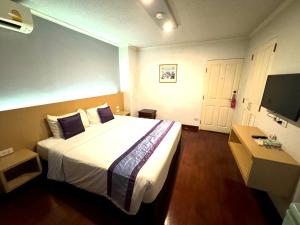 a hotel room with a large bed and a television at The Step Sathon in Bangkok
