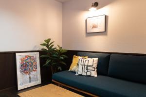 a blue couch in a room with a plant at 城崎温泉一棟貸し　旅宿YaDOKARI in Toyooka