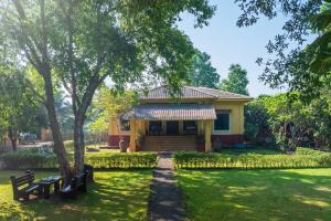 ein gelbes Haus mit zwei Bänken in einem Park in der Unterkunft Vintage Estate - Lakeside allure with vintage decor,A plunge pool & A lawn featuring a charming gazebo in Karjat
