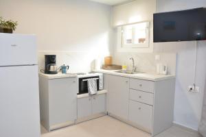een witte keuken met een wastafel en een magnetron bij Traveller's Nest Studio close to center,port,airport in Heraklion