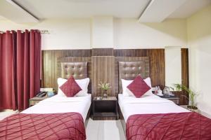 RTS Hotel Delhi Airport في نيودلهي: سريرين في غرفة الفندق مع ستائر حمراء