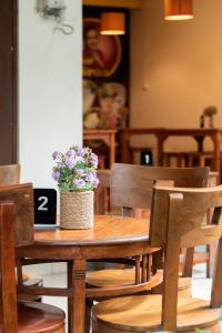 una mesa de madera con un jarrón de flores. en Miraa Guest House & Resto, en Denpasar