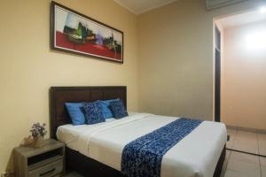 a bedroom with a large bed with blue pillows at Miraa Guest House & Resto in Denpasar