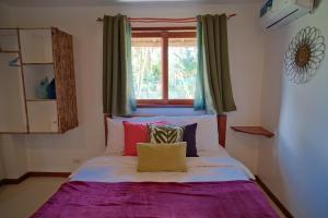 a bed in a room with a window at Copacabana Siargao in General Luna