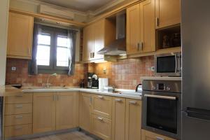 a kitchen with wooden cabinets and a sink and a microwave at Elatos Sea House in Kato Gatzea +29 photos