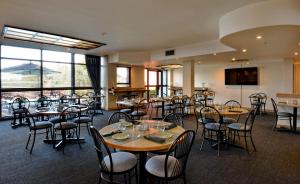 uma sala de jantar com mesas, cadeiras e janelas em Road Lodge Centurion em Centurion