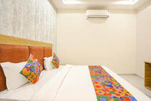 een slaapkamer met een bed met kleurrijke kussens bij FabHotel Maharishi inn in Ayodhya