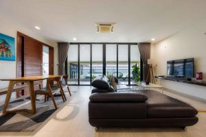 uma sala de estar com um sofá preto e uma mesa em Beach Haven Suites Hội An Apartment em Hoi An