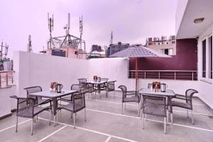 Hotel Emporio View - New Delhi Railway Station - Paharganj في نيودلهي: صف من الطاولات والكراسي على فناء على السطح