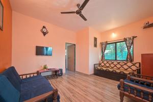 uma sala de estar com um sofá e uma ventoinha de tecto em Campion Villa em Lonavala
