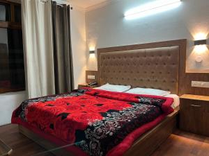 um quarto com uma cama grande e um cobertor vermelho em Hotel Premier Mall Road Manali em Manali