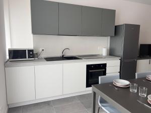 a kitchen with white cabinets and a black refrigerator at Quintarelli home Europa 1 in Negrar