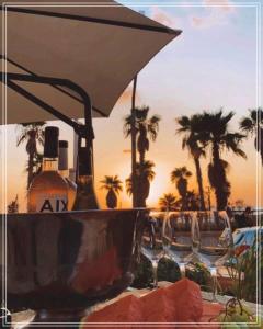 Bugrashov Beach 88 Hotel And Spa في تل أبيب: طاولة فيها مظلة وكراسي والنخيل