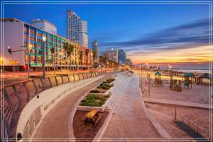 a city street with buildings and a beach at sunset at Bugrashov Beach 88 Hotel And Spa in Tel Aviv