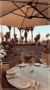 a table with wine glasses and an umbrella at Bugrashov Beach 88 Hotel And Spa in Tel Aviv