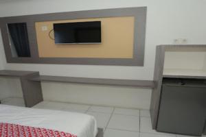 a room with a tv on a wall with a bed at Capital O 93730 Alima View Syariah in Bekasi