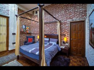 1 dormitorio con cama con dosel en una pared de ladrillo en SaffronStays Ekam Walnut Suite, Chail, en Kandāghāt